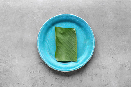 Plate with cut banana leaf on gray backgroundの写真素材