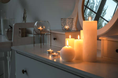 Many different candles on chest of drawers in roomの写真素材