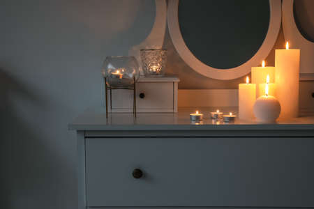 Many different candles on chest of drawers in roomの写真素材