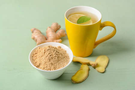 Cup of ginger tea and powder on color backgroundの写真素材