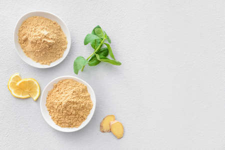 Bowls with ginger powder on light background