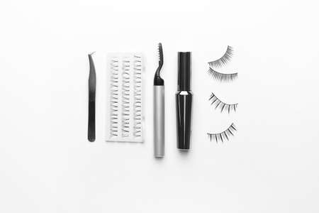 Composition with false eyelashes and tools on white background