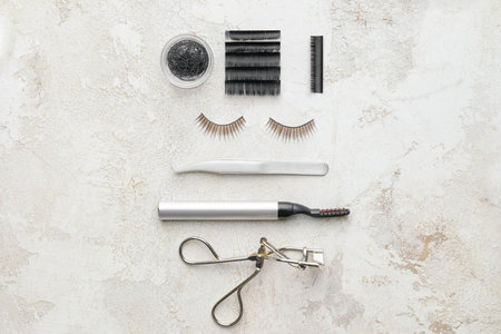 Composition with false eyelashes and tools on light background