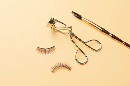 Curler, brush and false eyelashes on color backgroundの写真素材