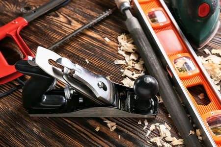 Set of carpenter's tools and saw dust on wooden background
