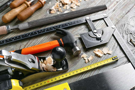 Set of carpenter's tools and saw dust on wooden background
