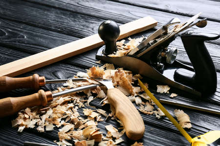 Set of carpenter's tools and saw dust on dark wooden background