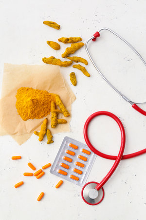 Blister pack with turmeric pills and stethoscope on light backgroundの写真素材