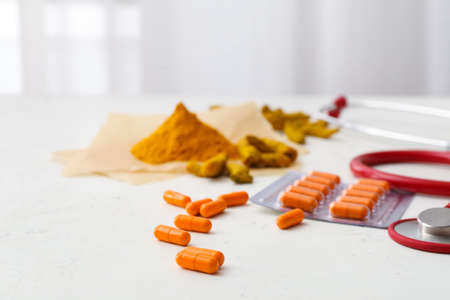 Turmeric pills and stethoscope on light backgroundの写真素材
