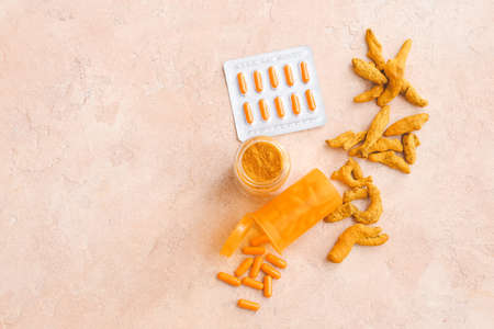 Bottles with turmeric pills and powder on color backgroundの写真素材