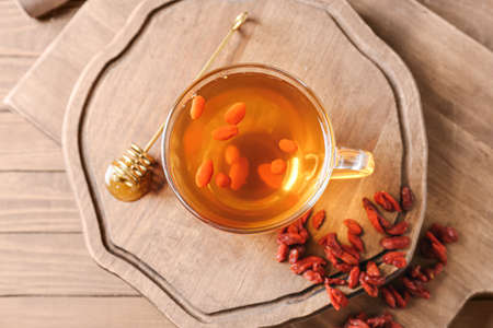 Glass cup of hot tea with goji berries on wooden backgroundの写真素材