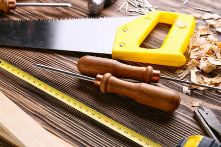 Set of carpenter's tools and saw dust on wooden background
