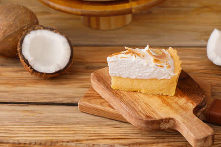 Board with piece of tasty coconut pie on wooden backgroundの写真素材