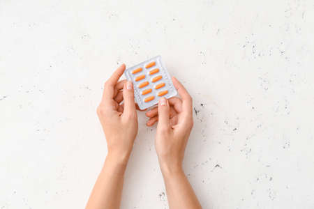 Female hands and blister pack with turmeric pills on light backgroundの写真素材