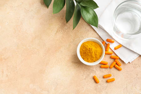 Turmeric pills and bowl with powder on color backgroundの写真素材