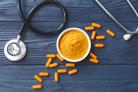 Turmeric pills, powder and stethoscope on dark wooden backgroundの写真素材