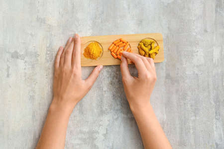 Female hands with turmeric pills, powder and roots on grunge backgroundの写真素材