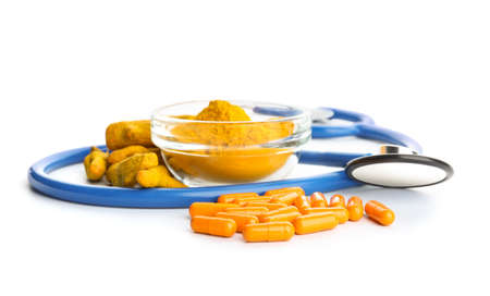 Turmeric pills, powder and stethoscope on white backgroundの写真素材