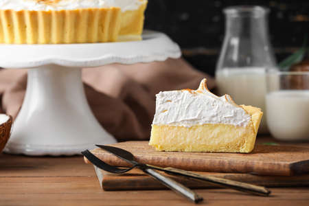 Board with piece of tasty coconut pie on wooden backgroundの写真素材