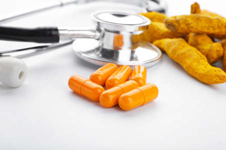 Turmeric pills and stethoscope on white backgroundの写真素材