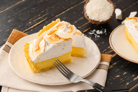 Plate with pieces of tasty coconut pie on dark wooden backgroundの写真素材