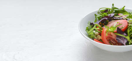 Bowl with tasty fresh salad on white background with space for textの写真素材