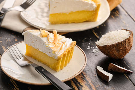 Plate with piece of tasty coconut pie on dark wooden backgroundの写真素材