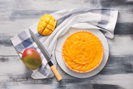 Board with tasty mango pie on wooden backgroundの写真素材