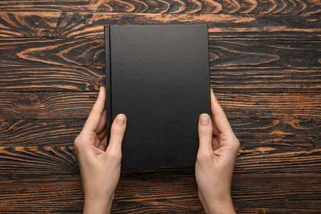 Woman holding book on wooden backgroundの写真素材