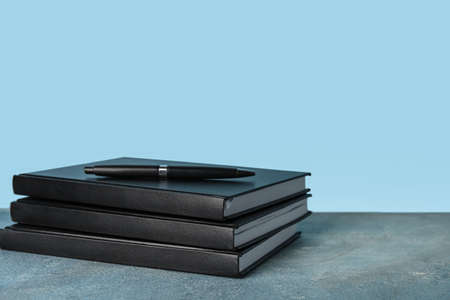 Stack of books and pen on color backgroundの写真素材