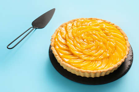 Tasty mango pie and spatula on color backgroundの写真素材