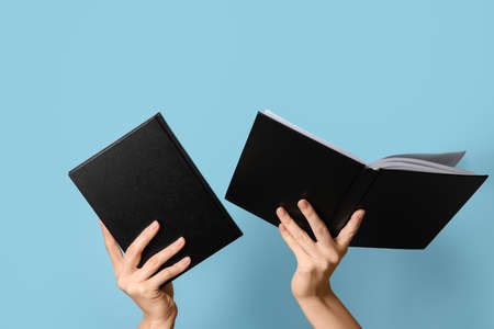 Woman holding books on color backgroundの写真素材