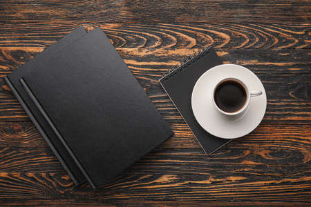 Blank book, notebook and cup of coffee on wooden backgroundの写真素材