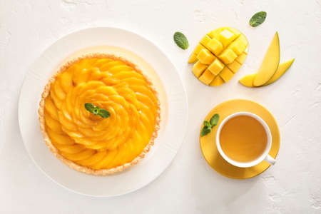 Plate with tasty mango pie and cup of tea on light backgroundの写真素材