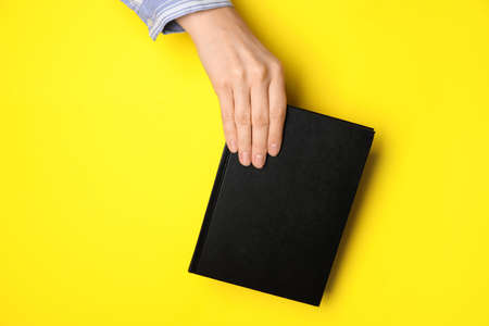 Woman holding book on color backgroundの写真素材