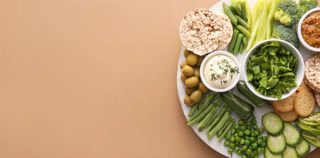 Board with different green vegetables and snacks on color background with space for textの写真素材