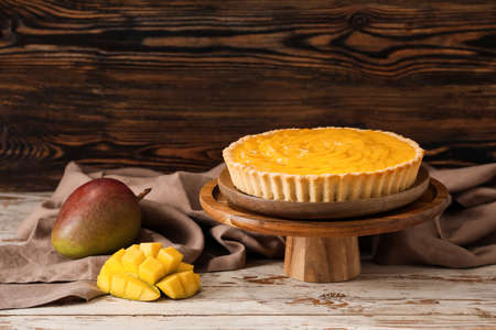 Dessert stand with tasty mango pie on wooden backgroundの写真素材