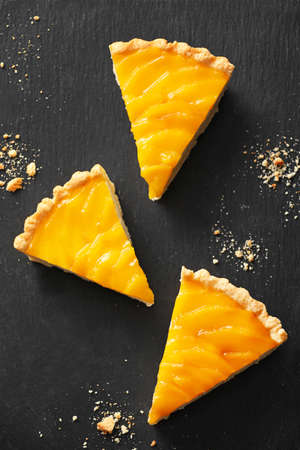 Pieces of tasty mango pie on dark backgroundの写真素材