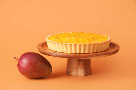 Dessert stand with tasty mango pie on color backgroundの写真素材