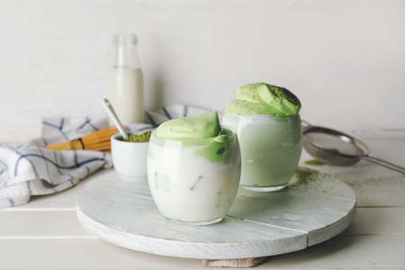 Tray with glasses of tasty dalgona matcha latte and powder on light wooden backgroundの写真素材
