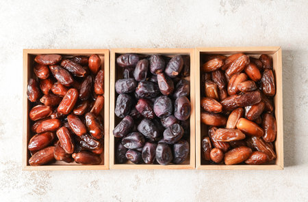 Wooden boxes with sweet dried dates on light background