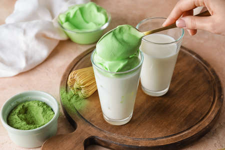 Woman preparing tasty dalgona matcha latte on tableの写真素材