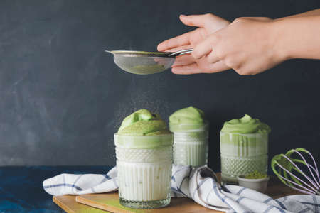 Woman preparing tasty dalgona matcha latte on dark backgroundの写真素材
