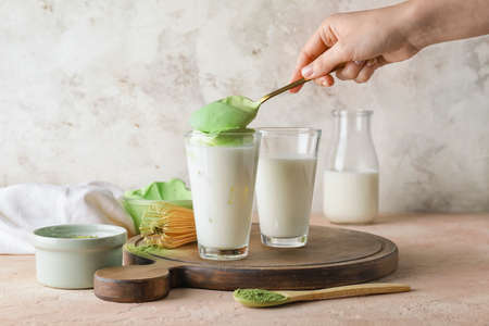Woman preparing tasty dalgona matcha latte on tableの写真素材