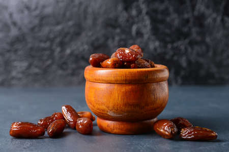 Bowl with sweet dried dates on dark background