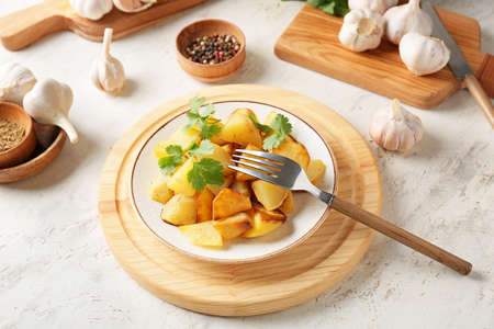 Plate of tasty baked potato with garlic on light backgroundの写真素材