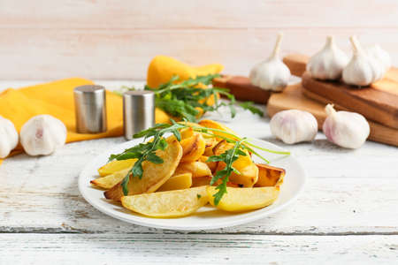 Plate of tasty baked potato with garlic on light wooden backgroundの写真素材