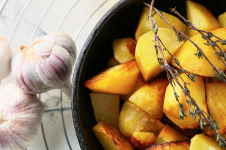 Frying pan of tasty potato with garlic on light backgroundの写真素材