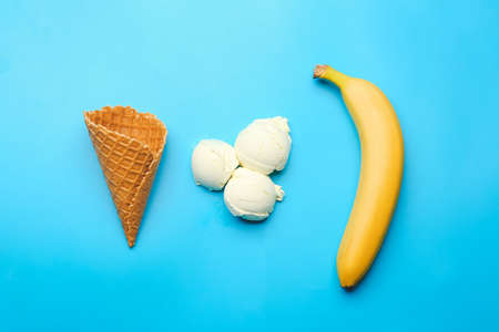 Composition with waffle cone, tasty ice cream and banana on color background