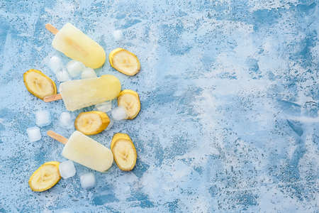 Tasty banana ice-cream and ice cubes on color background
